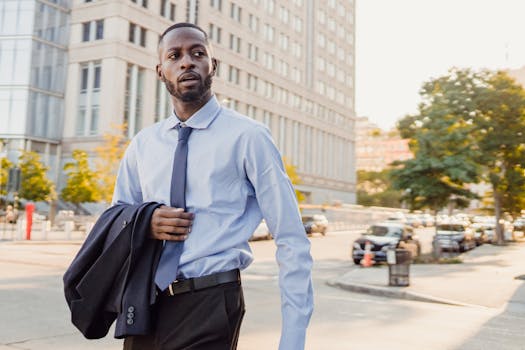 Business professional walking in the city with confidence, carrying jacket and wearing a tie.