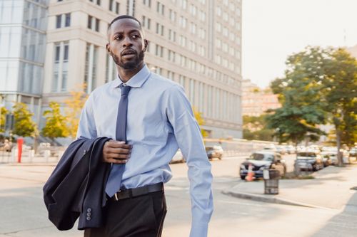Free Business professional walking in the city with confidence, carrying jacket and wearing a tie. Stock Photo