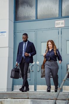 Two business professionals leaving an office building through exit doors.