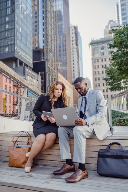 Free Two business professionals on a city bench working on a laptop. Stock Photo