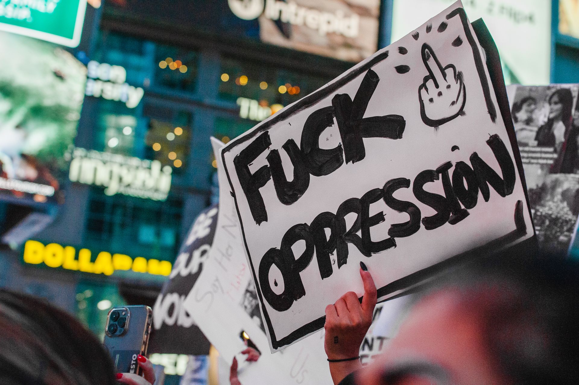 Protesters holding a bold sign against oppression in a lively city scene.