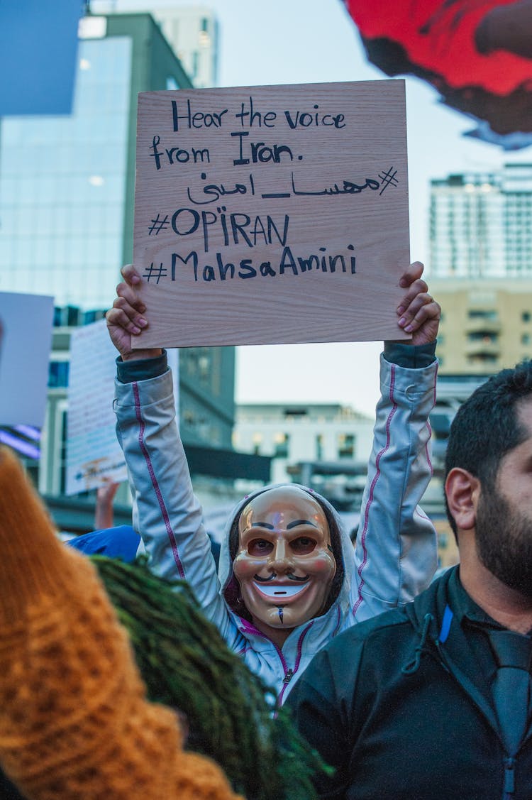 Person Wearing An Anonymous Mask Holding A Sign