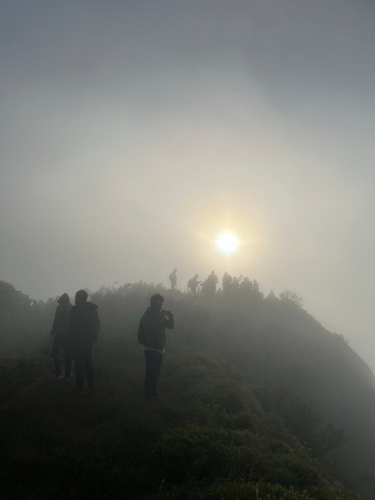 Silhouettes Of People Standing On Top Of Misty Mountain