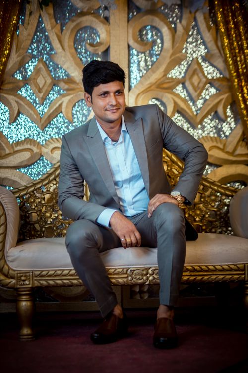 Free Confident man in a suit sitting on a luxurious sofa with intricate golden details. Stock Photo