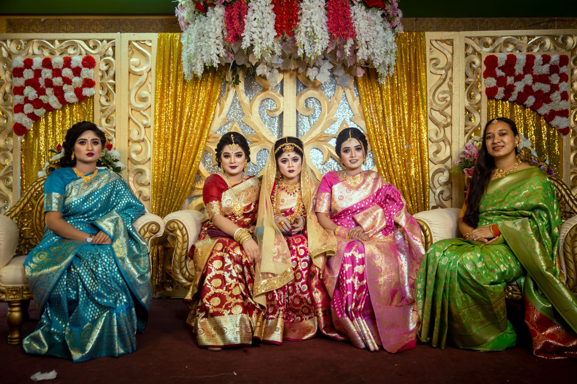 Colorful Indian bride and bridesmaids in traditional sarees at a wedding celebration.