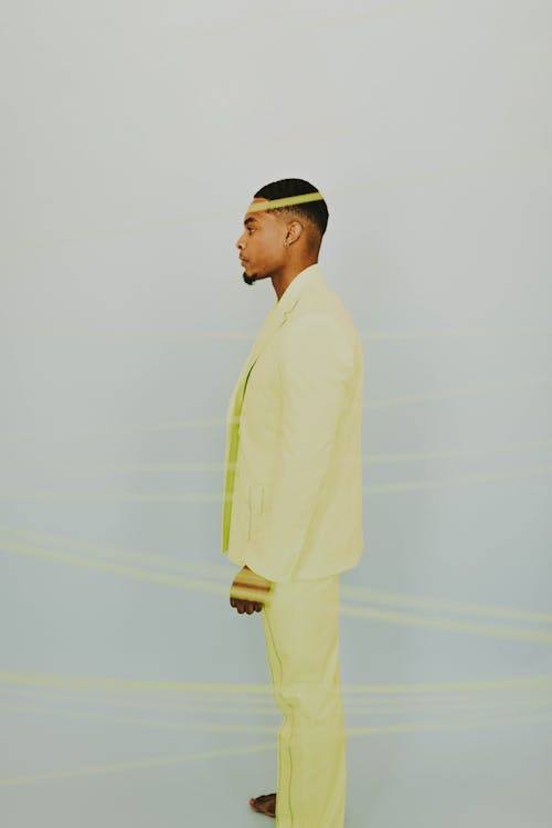 Side View of a Young Man in a Yellow Suit Posing in Studio 