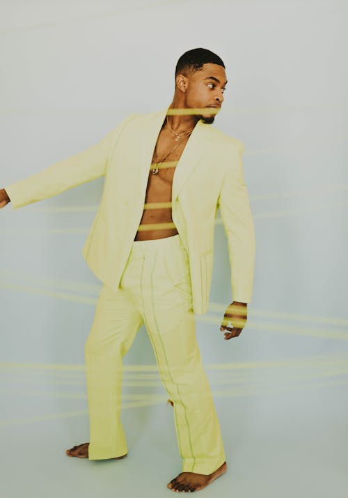 A Man in Yellow Suit and Pants Standing Barefooted while Looking Over Shoulder