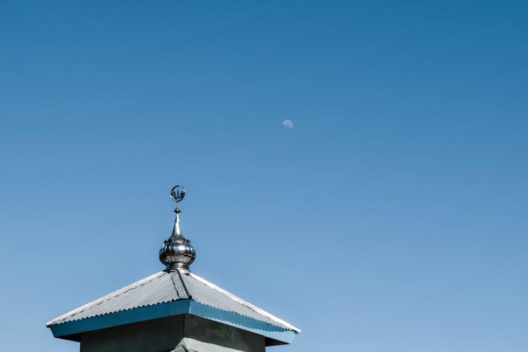 Moon Rising Against A Clear Sky With A Finial In The Foreground