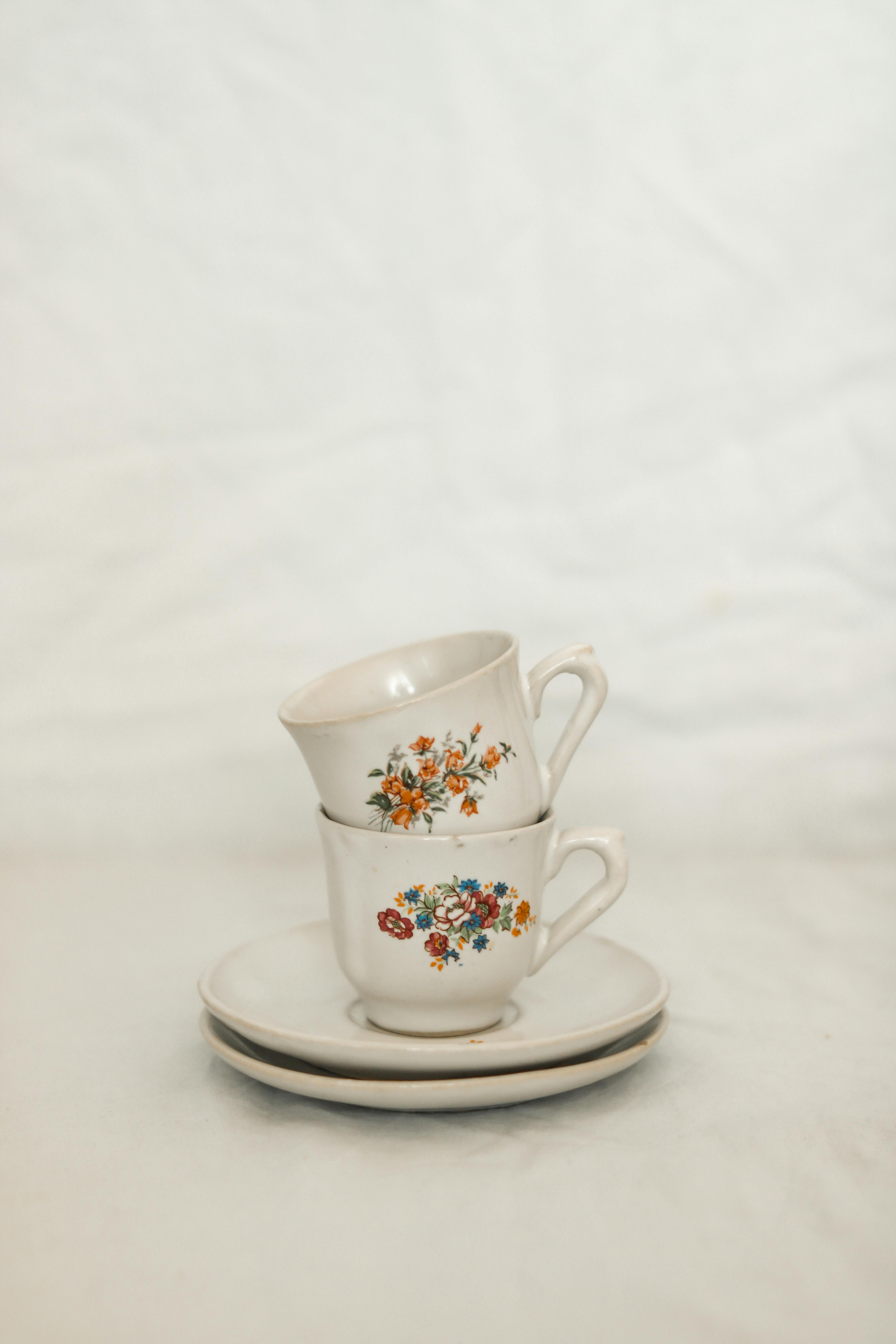 Stacked floral porcelain teacups on saucers in a minimalist style, offering a clean, elegant look.