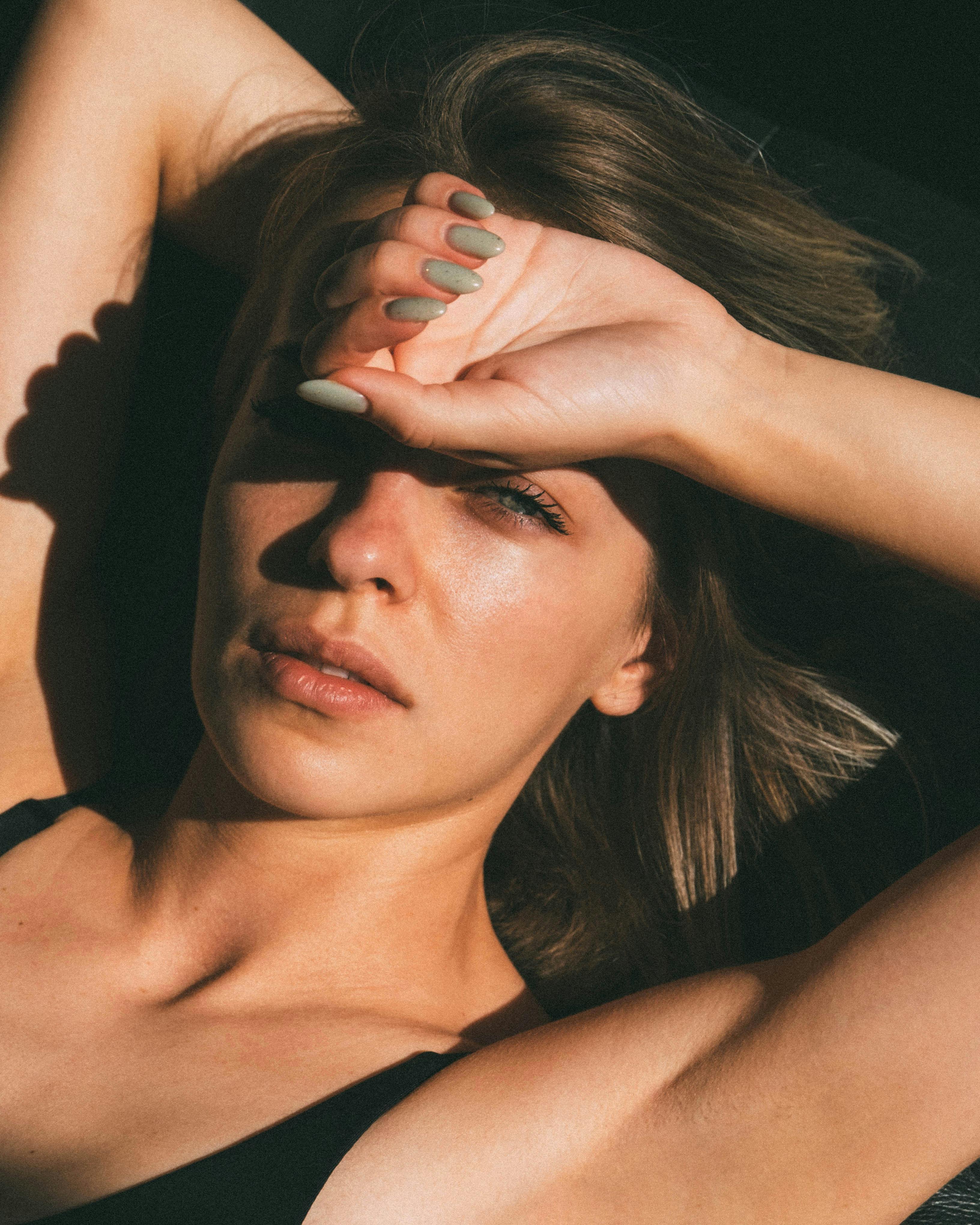 一个女人的特写肖像用手遮住眼睛免受阳光照射