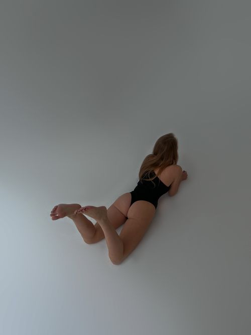 Free A woman lies on the floor wearing a black swimsuit, viewed from a high angle. Stock Photo
