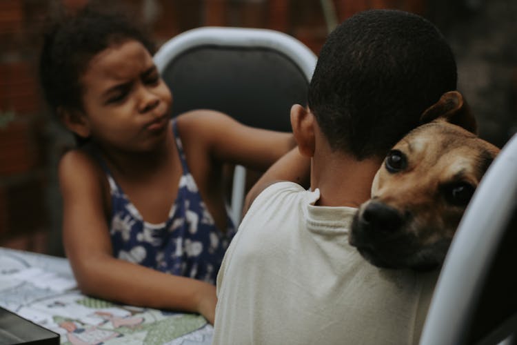 Boy Cuddling A Dog Beside A Girl