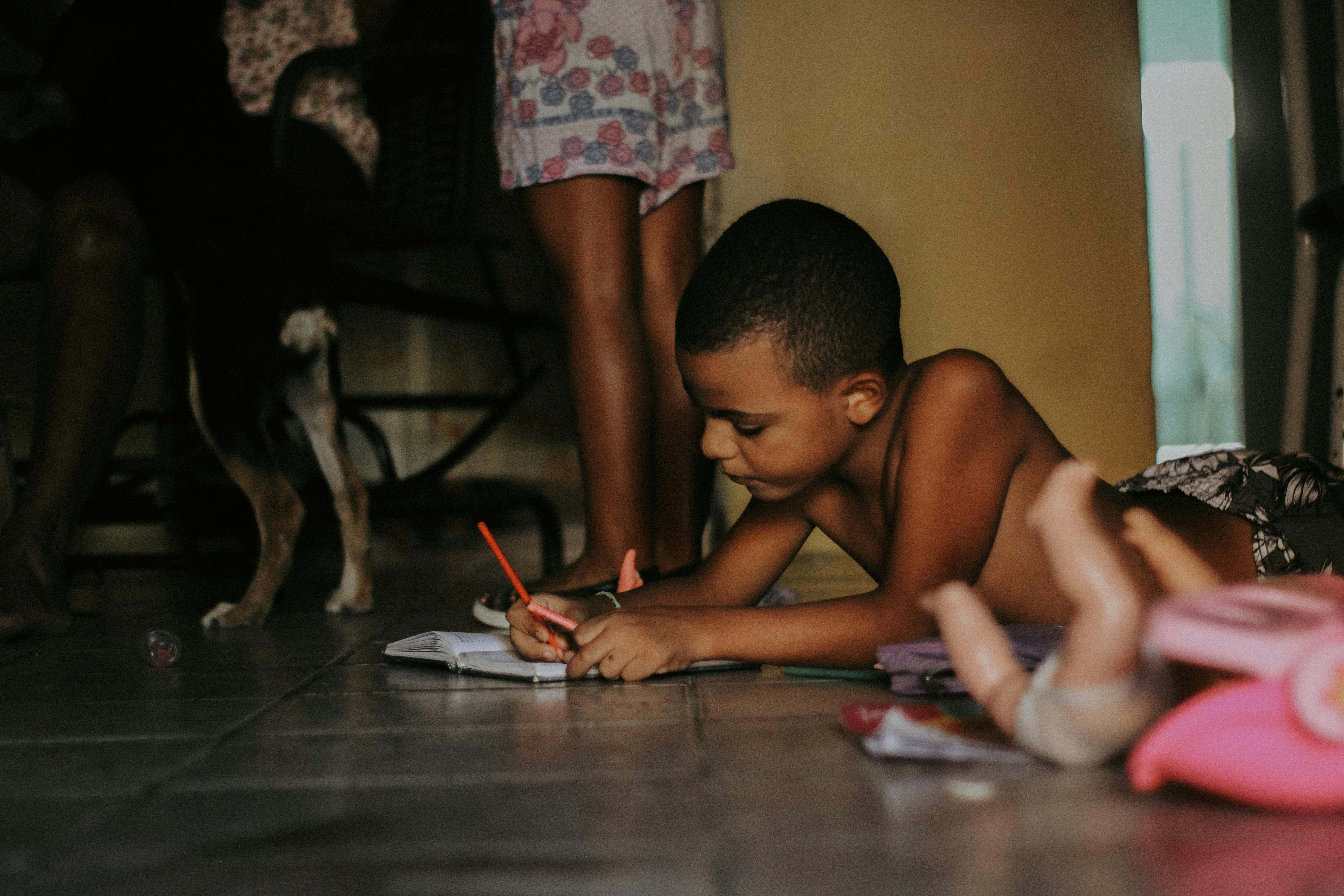 photograph of a shirtless boy drawing