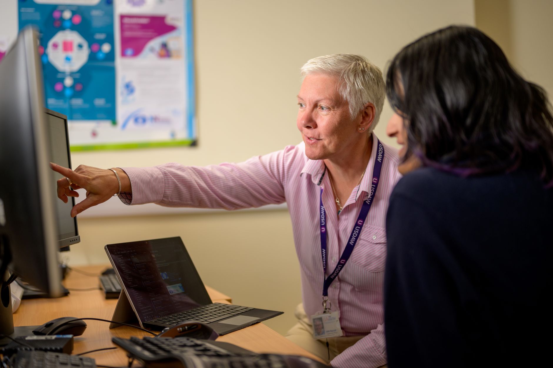Two colleagues, one older and one younger, working through a career transition plan at a computer.