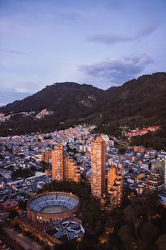 Stunning aerial view of Bogotá, Colombia with cityscape and surrounding mountains at dusk.
