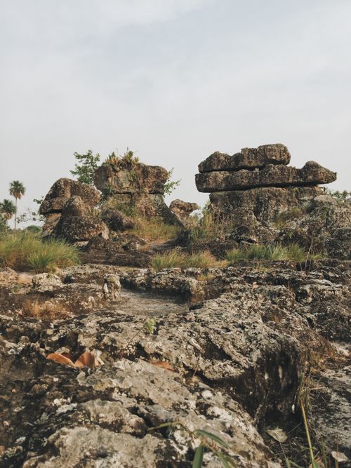 Free Majestic ancient rock formations surrounded by lush vegetation in a serene natural setting. Stock Photo