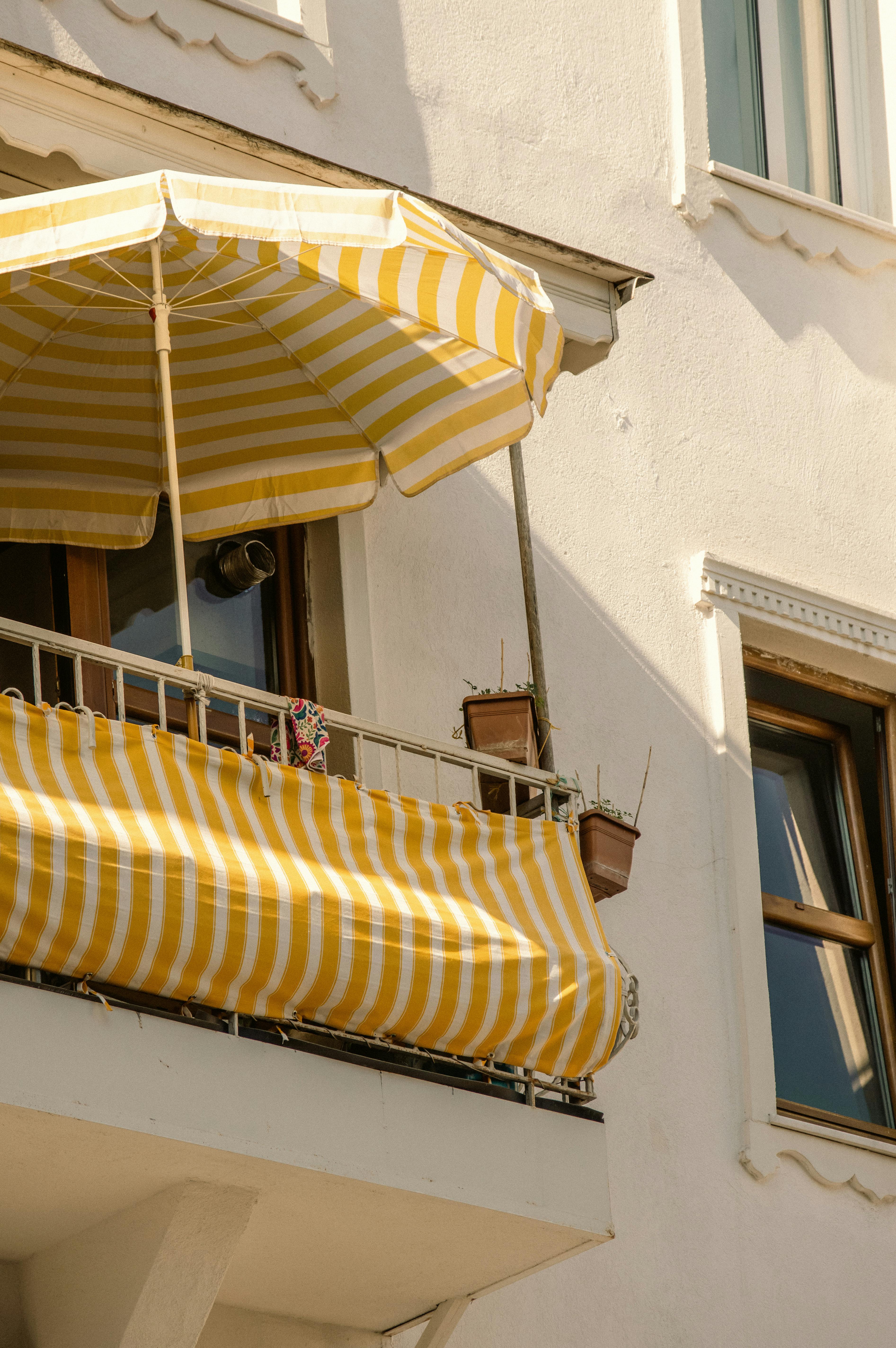 Free Charming summer scene featuring a striped umbrella on a residential balcony in Arnavutköy, Istanbul. Stock Photo