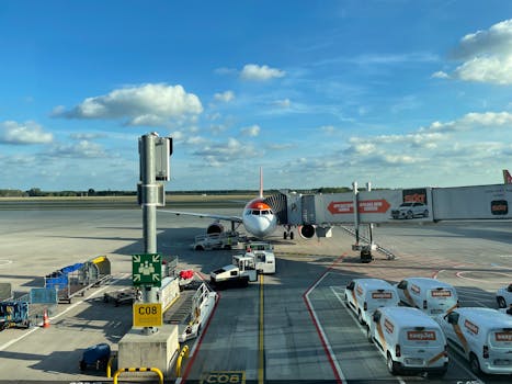 EasyJet airplane stationed at Schönefeld Airport gate with support vehicles surrounding.