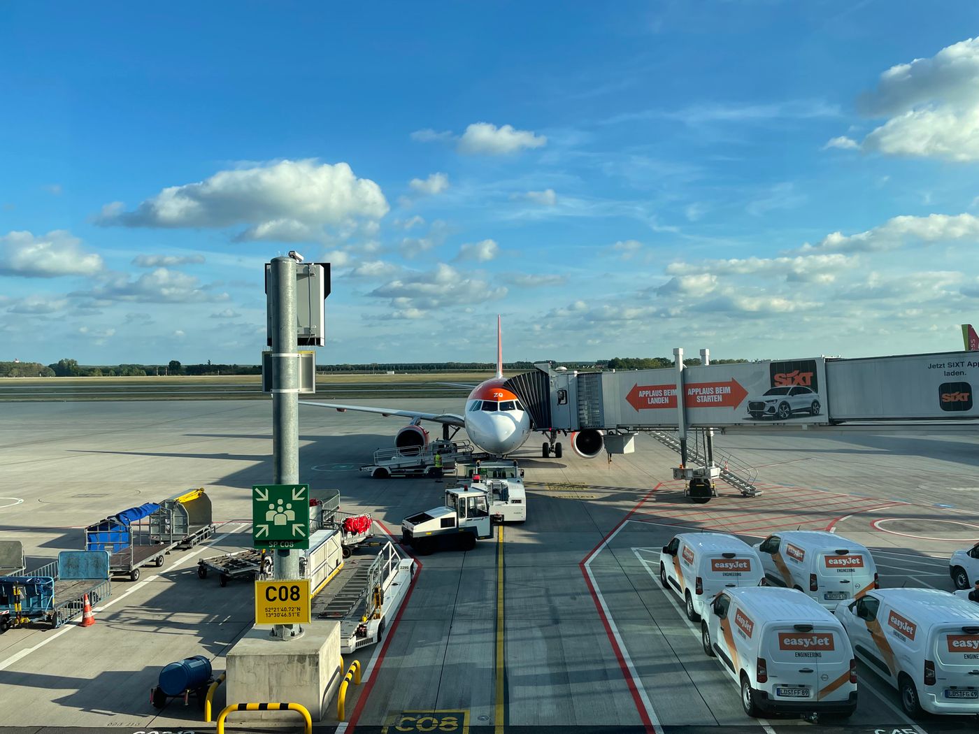 An easyJet aircraft parked at a gate at Schönefeld airport with ground vehicles around it