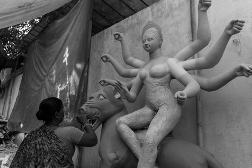 Free A woman artist works on a clay sculpture of a Hindu goddess in a workshop setting. Stock Photo