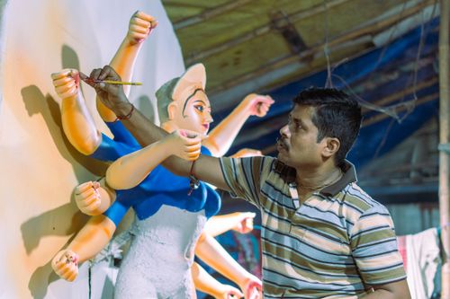 Free A man artistically paints a Durga statue in a traditional workshop setting. Stock Photo