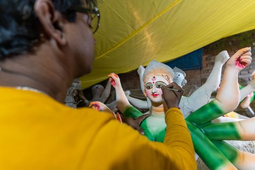 Free A skilled artisan meticulously paints a traditional Hindu goddess statue, showcasing vibrant artistry and cultural heritage. Stock Photo