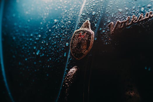 Artistic close-up of a car hood with water droplets, emphasizing texture and lighting.