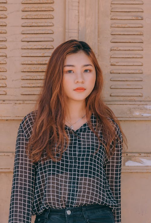 Woman Wearing Blouse and Denim Bottoms Standing Against the Wall