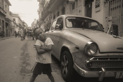 Boy Posing Near an Old Car on a Street 