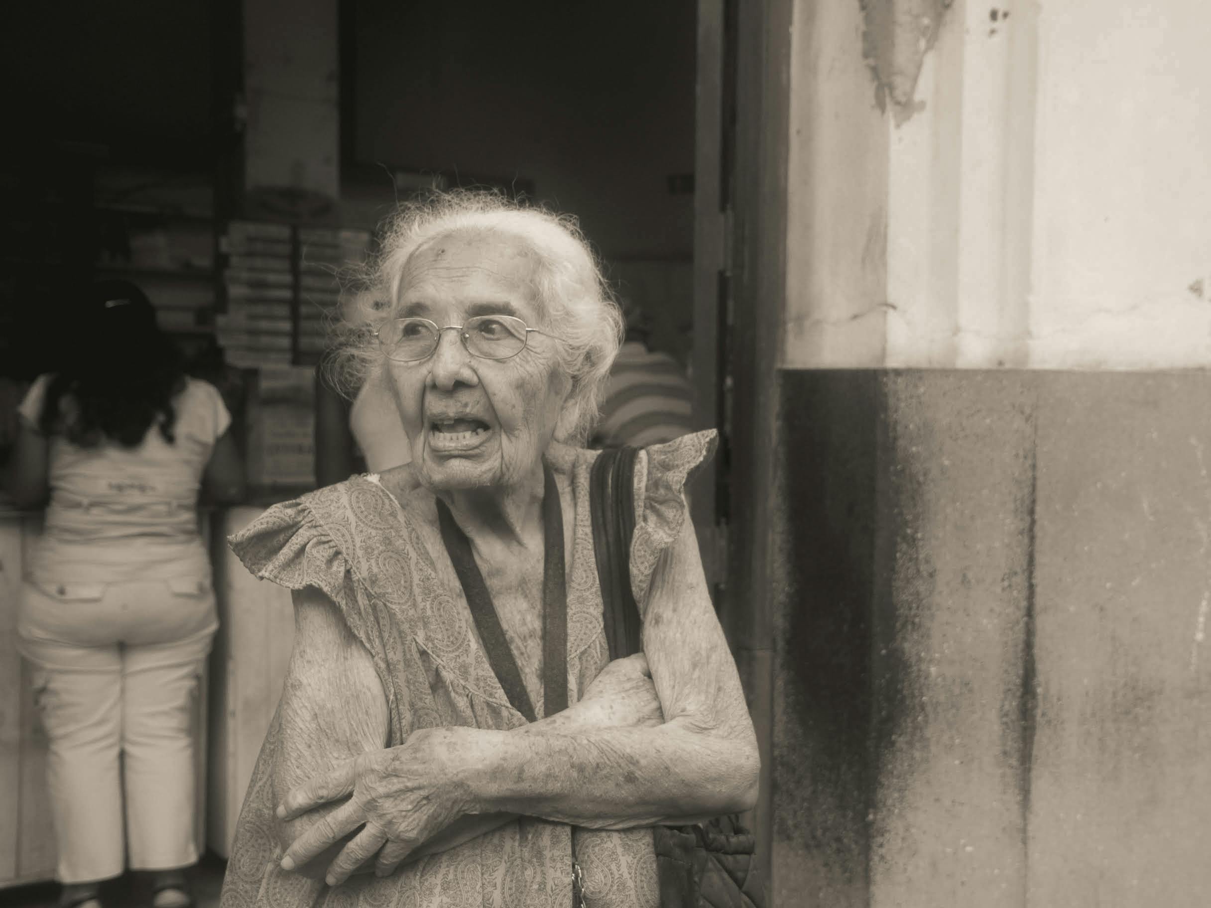 grayscale photography of an elderly woman standing while looking afar