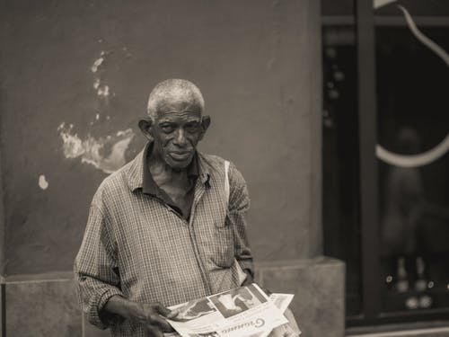 Elderly Man in Striped Button Up Shirt Holding a Newspaper