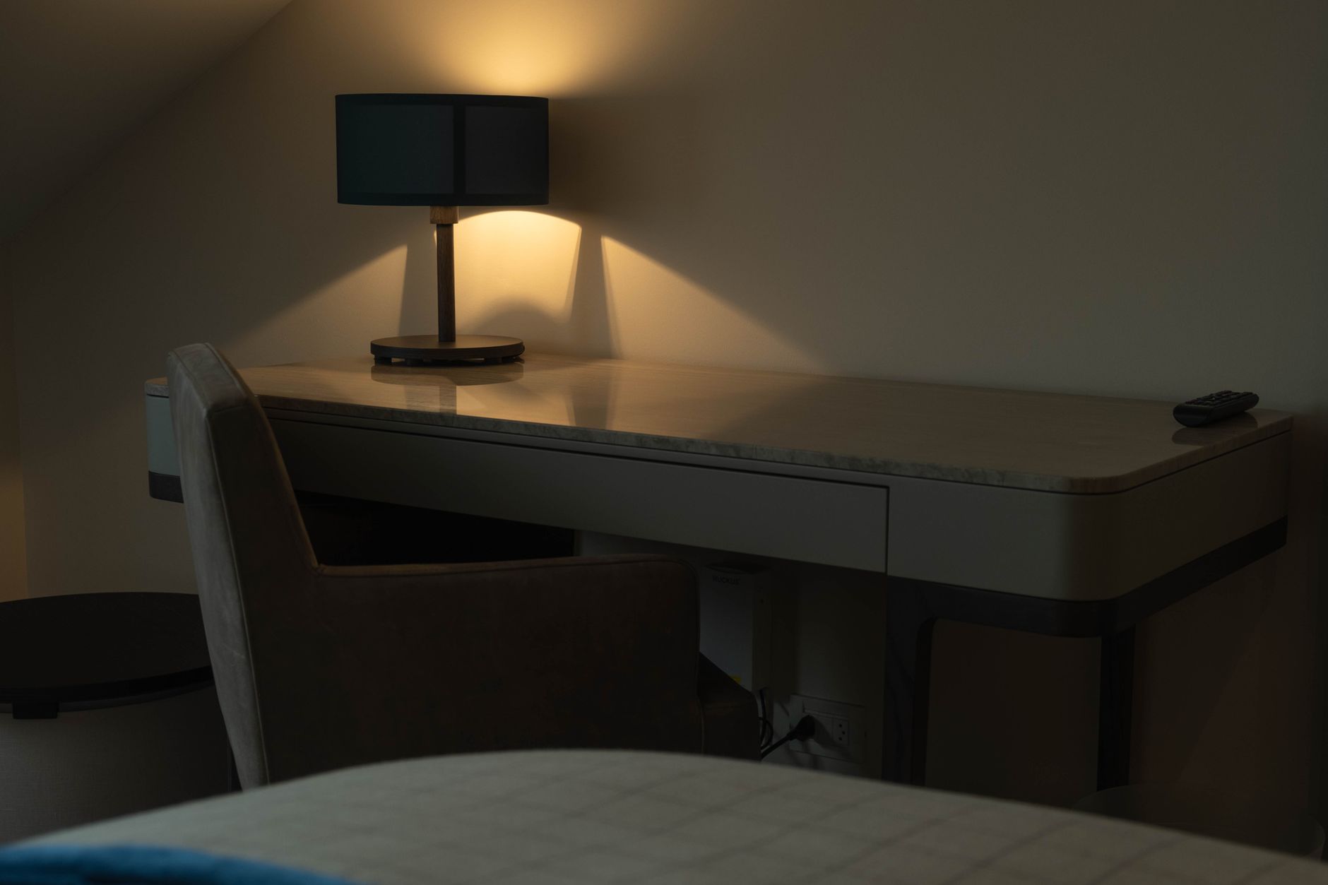A minimalist desk setup with a modern lamp casting warm light in a cozy bedroom setting.
