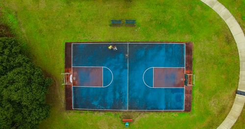 Free Top-down view of a vibrant outdoor basketball court set in a lush green park, captured brilliantly from above. Stock Photo