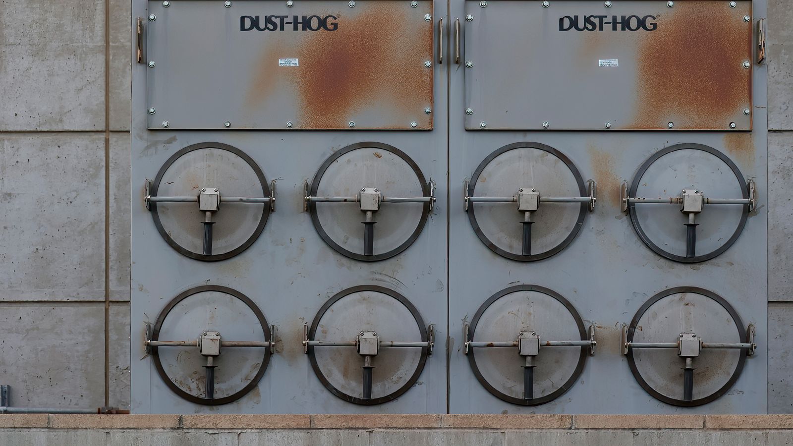 Close-up of a Dust-Hog industrial dust collector with six rusty filtration units.
