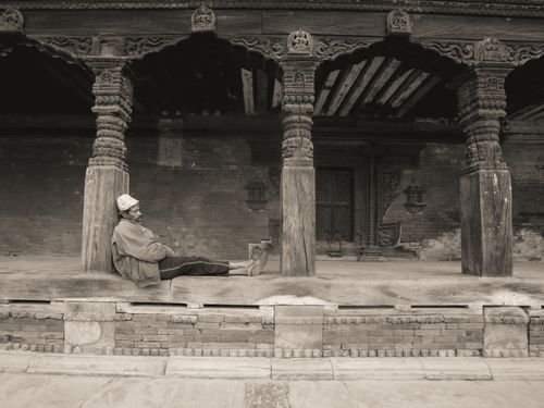 Free A man relaxes in a historic temple with intricately carved columns, Nepal. Stock Photo