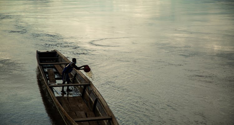 Man Pouring Water Out Of Leaking Boat