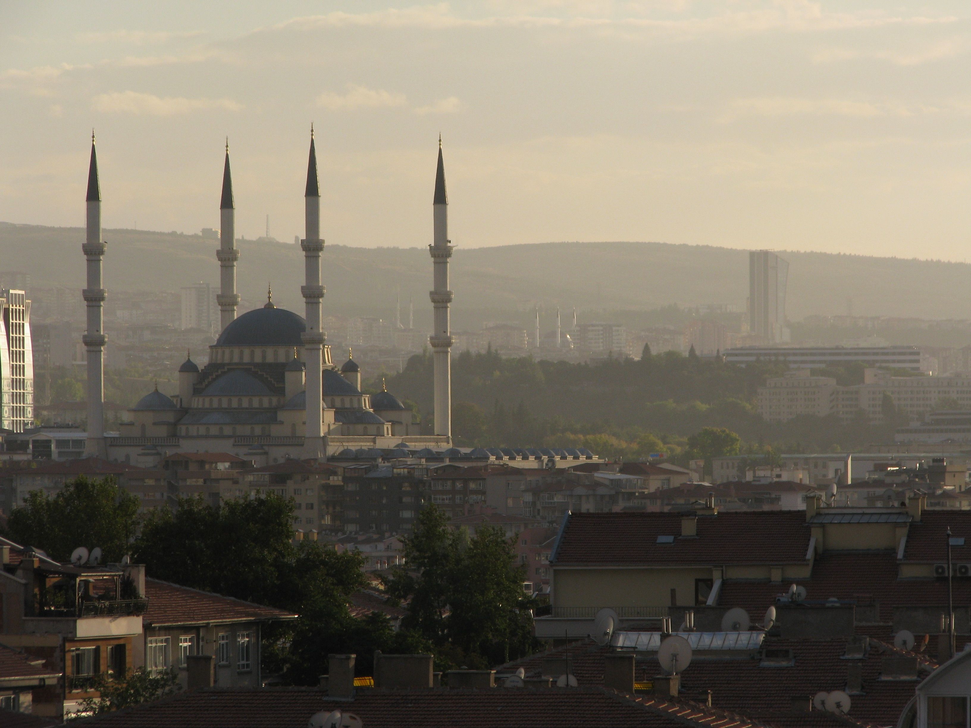 A beautiful cityscape showcasing a mosque with a backdrop of urban skyline during sunset, capturing Islamic architecture.