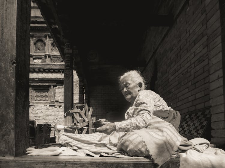 Black And White Photo Of Elderly Woman Spinning Yarn