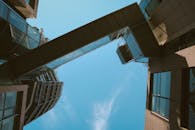 低角度镜头拍摄蔚蓝天空下建筑物间的现代天桥