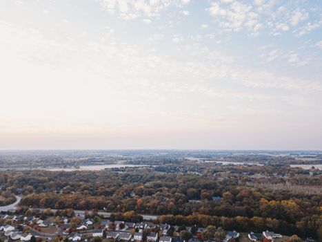 Peaceful aerial photo of suburban houses and lush greenery during fall, perfect for real estate or travel themes.