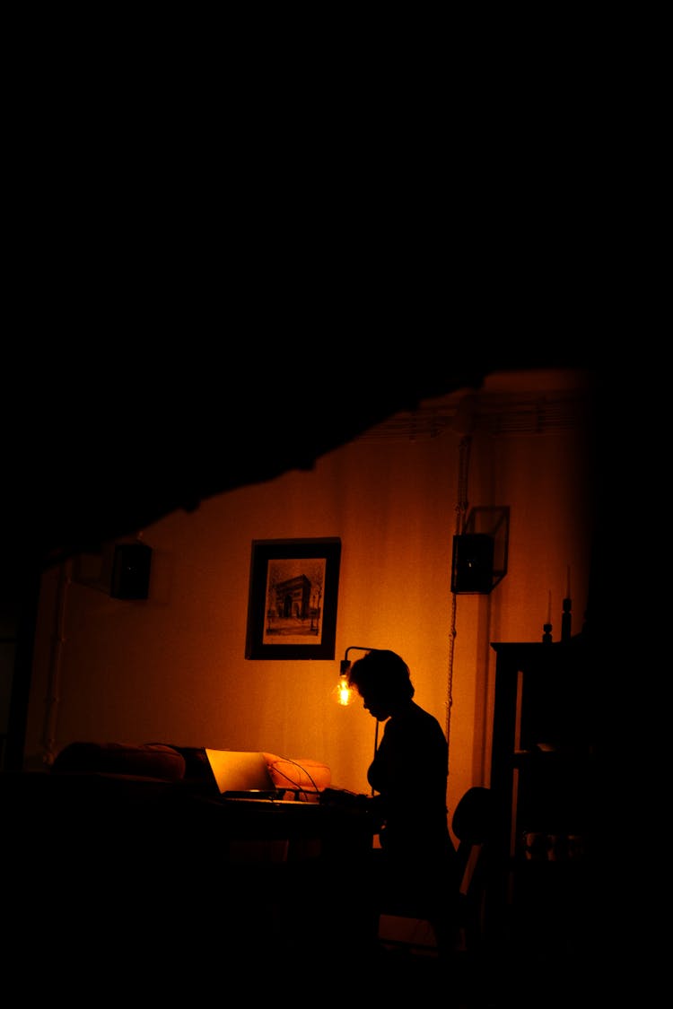 Silhouette Of A Woman Sitting In A Dark Room 