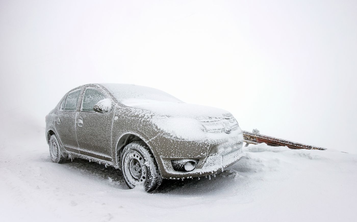 Car coated in ice and snow parked outside in freezing weather