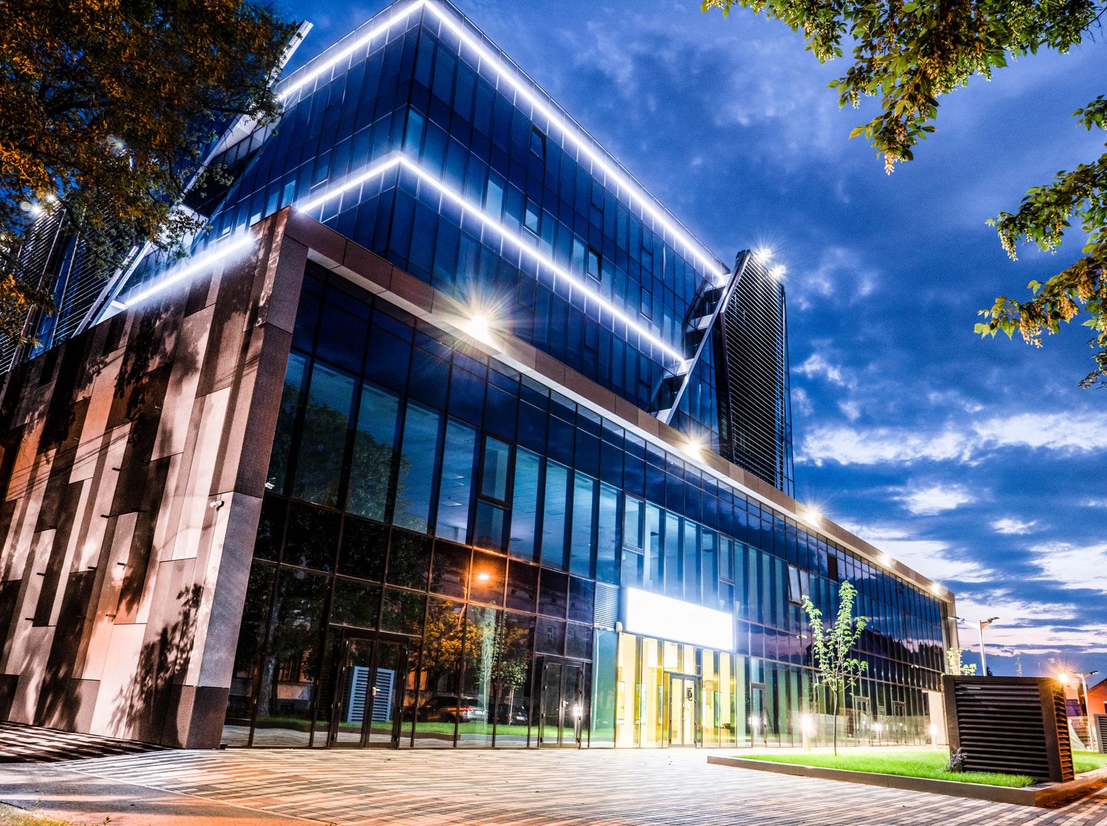 Glass-fronted retail building lit at dusk — photo by Adrian Frentescu on Pexels