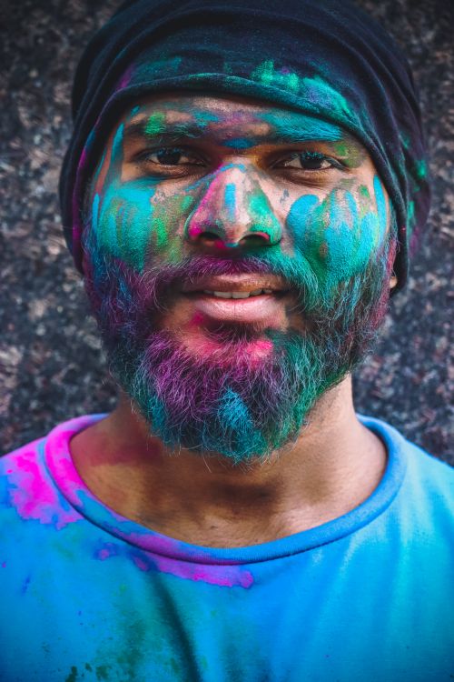 Free Close-up portrait of a man with vibrant face paint celebrating Holi. Stock Photo