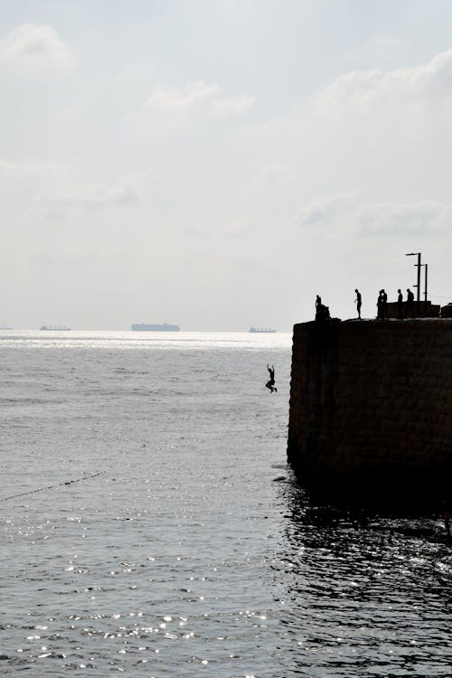 A Silhouette of a Person Jumping on a Cliff