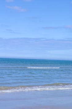 A tranquil beach scene in France with calm waves and a clear blue sky, perfect for relaxation.