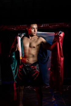 A male MMA fighter posing proudly with the Mexican flag, showcasing national pride.