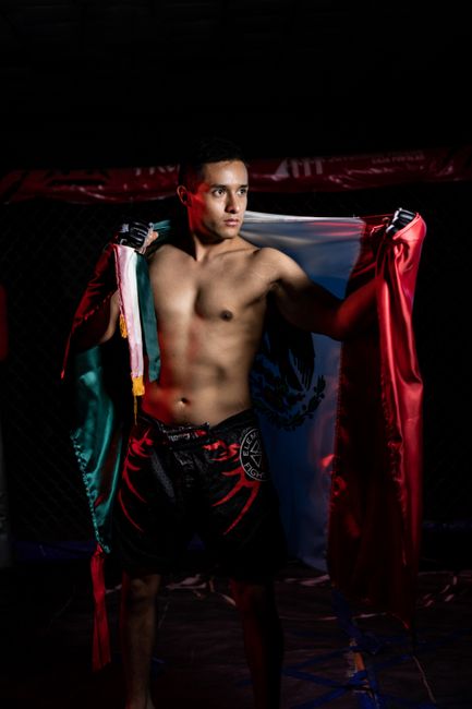 Fotomural Un luchador masculino de MMA posando orgullosamente con la bandera mexicana, mostrando orgullo nacional.