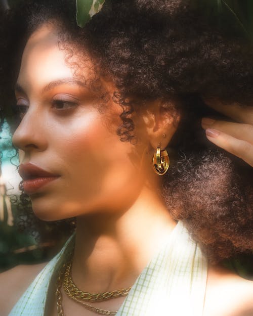 Woman with Curly Hair Wearing Gold Earrings and Gold Necklaces