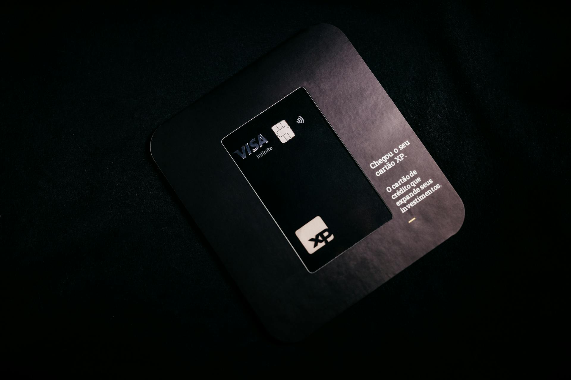 A Visa XP black credit card displayed on a dark background, emphasizing finance and security.